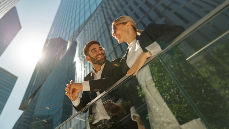 Dos profesionales conversando sobre inversión frente a un edificio de oficinas