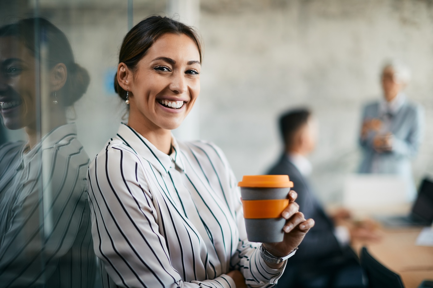 Young happy businesswoman enjoying in coffee break in the office and looking at camera.